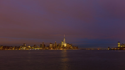 Low Manhattan skyline at night with reflection in Hudson River. Metropolis urban landscape in winter, New York, USA.