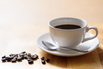 Cup of hot coffee and roasted coffee bean on wooden table