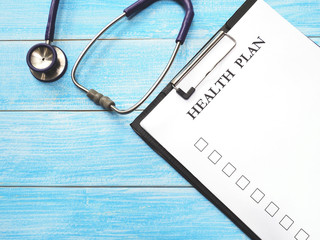 clipboard with white paper and stethoscope on wooden background.