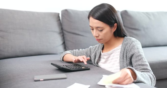 Woman calculating the expense on calculator, and feeling shock after the result