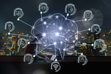 Polygonal brain shape of an artificial intelligence with various icon of smart city Internet of Things Technology over businessman using laptop with cityscape background, AI and business IOT concept