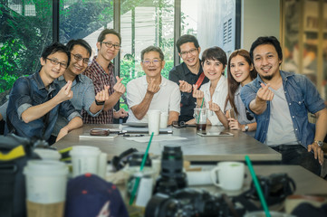 Obraz premium Group Of Asian Business people with casual suit doing small heart with happy action and celebrate in the Office or coffee shop, people business group concept