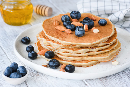 Gluten free oat pancakes with blueberries and almonds on white plate. Closeup view