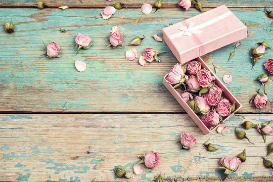 Fototapeta Gift box with pink dried rose flowers on old  turquoise wooden background with copy space. Flowers composition.
