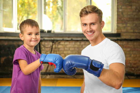 Little boy with trainer in boxing gloves indoors