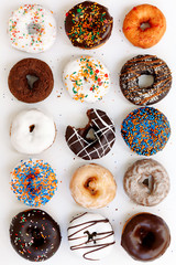 assorted donuts with chocolate frosted, white glazed and sprinkled donuts on white background, top view - obrazy, fototapety, plakaty