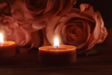 Beautiful burning candles and roses in darkness