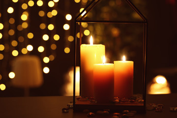 Beautiful burning candles in darkness against defocused lights