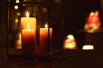 Beautiful burning candles in darkness against defocused lights