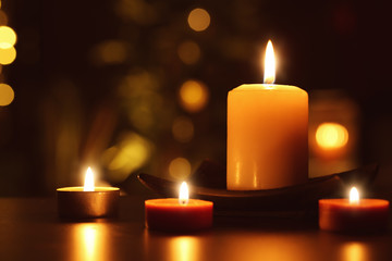 Burning candles in darkness against defocused lights