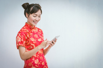 Asian woman with cheongsam holding smartphone.