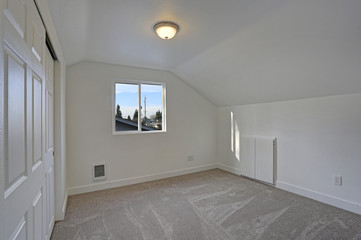 Empty bedroom interior with vaulted ceiling on the upper floor.