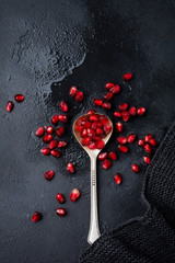 Fresh ripe pomegranate, cut into pieces on black concrete or stone background. Selective focus. Place for text. Top view.