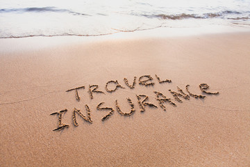 travel insurance concept, text words written on the sand