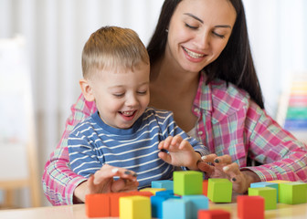Child boy together with mother playing toys