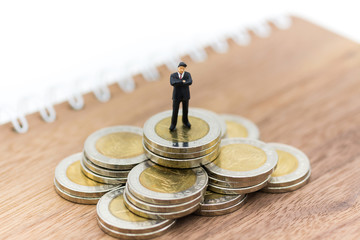 Miniature person: Businessman figure standing on stack of coins. Image use for business, financial concept.