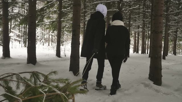 A mixed race couple searching for and cutting down a Christmas Tree