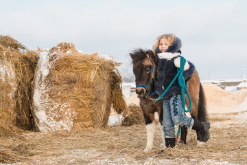 Small girl and small horse in a winter
