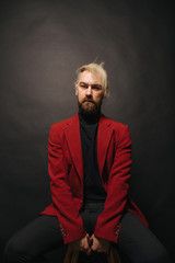 Obraz premium Indoor shot of handsome blond beard male with calm expression, dressed in fashionable jacket, remember something, black background with copy space for your promotional text
