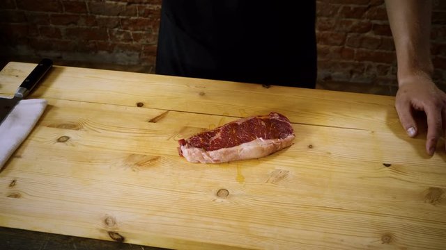 Cooking meat. Cook adding olive oil to a juicy raw beef steak. 4K