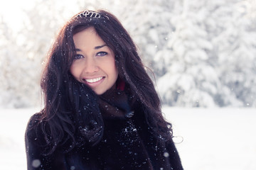 beautiful brunette girl in a fur coat on background of a winter forest
