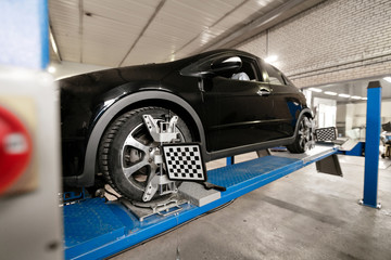 Grid sensor sets mechanic on auto. Car stand with sensors wheels for alignment camber check in workshop of Service station.