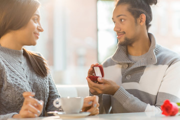 Romantic guy making proposal to his girlfriend on Valentine day and showing her engagement ring in small box