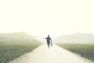 Obraz premium man with suitcase runs fast on a deserted road to an unknown destination