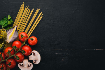 Spaghetti with fresh vegetables and spices. Italian Traditional Cuisine. On a wooden background. Top view. Copy space.