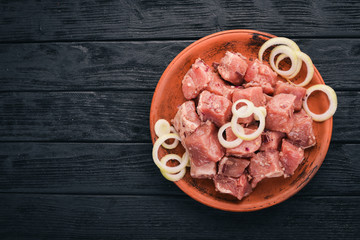 Raw uncooked meat sliced in cubes on wooden rustic background, top view.