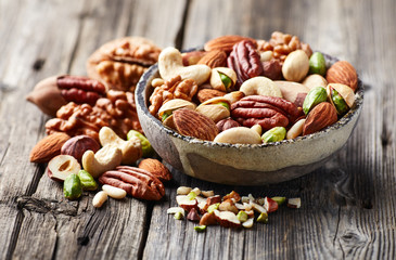 Mixed and cut nuts on a wooden background