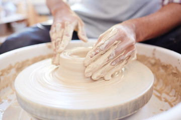 Hands of potter on rotating fireclay machine creating new earthenware