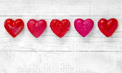 Luxury red hearts on white wooden background. Happy Valentines day. Glitter love confetti.