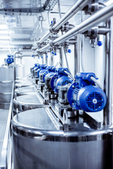 Rows of blue electric motors on tanks for mixing liquids.