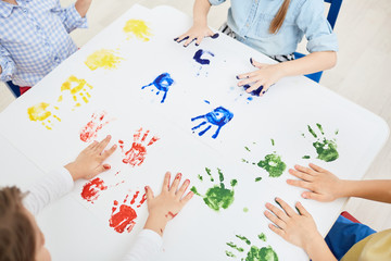 Fototapeta na wymiar Kindergarten kids making colorful hand prints on paper while having fun at leisure