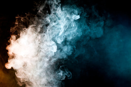 Dense multicolored smoke of   red, blue on a black isolated background. Background of smoke vape