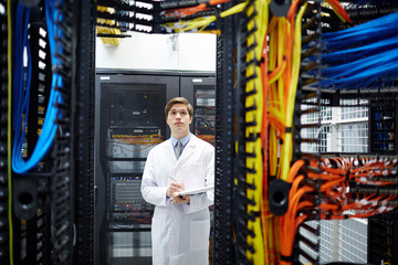 Serious programmer in whitecoat carrying out check-up of new hardware in mining farm