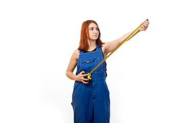 Young attractive woman in blue construction overalls smiling and holding in hands an open yellow construction ruler on white isolated background