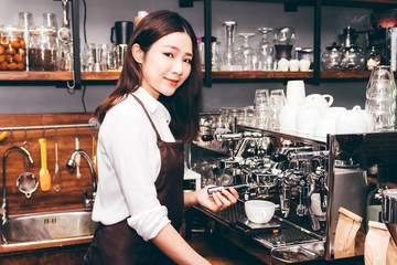 Women Barista using coffee machine for making coffee in the cafe