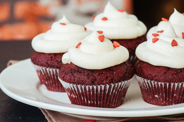 Red velvet cupcakes with cream cheese frosting on a white plate