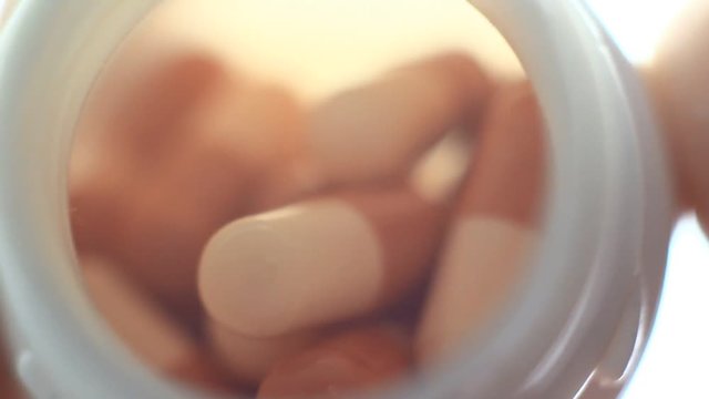 Pills in a plastic containet. Close up. Macro. Soft light from back.