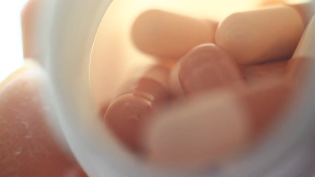 Pills in a plastic containet. Close up. Macro. Soft light from back.