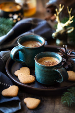 Cozy table setting with two cups of espresso coffee served with heart shaped cookies