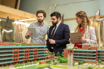 Group of confident city designers discussing online pictures of modern urban views