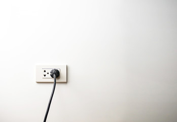Black electric cord plugged into a socket