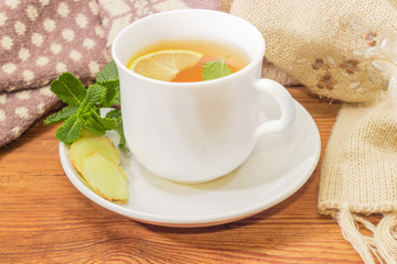 Tea with lemon, mint, ginger against of woolen mittens, scarf