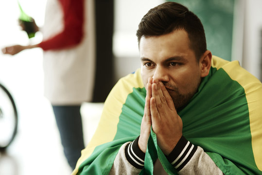 Nervous football fan with flag praying