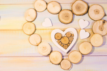The concept of St. Valentine's Day, Love, Wedding, Anniversary with wooden hearts in a heart shaped frame of tree circles, colored wooden background, top view