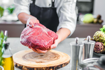 Koch in der Küche mit großem stück Steak Fleisch