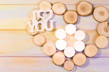 The concept of St. Valentine's Day, Love, Wedding, Anniversary with six burning aroma candles and I Love You inscription in a heart shaped frame of tree circles, colored wooden background, top view